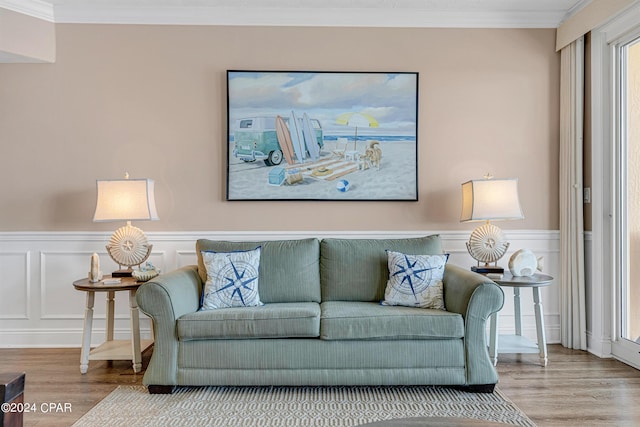 living area featuring a wainscoted wall, wood finished floors, and crown molding