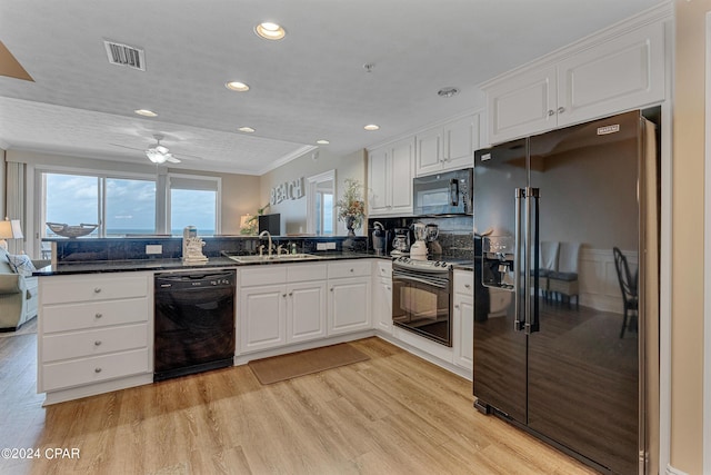 kitchen with visible vents, light wood-style flooring, a sink, black appliances, and white cabinetry