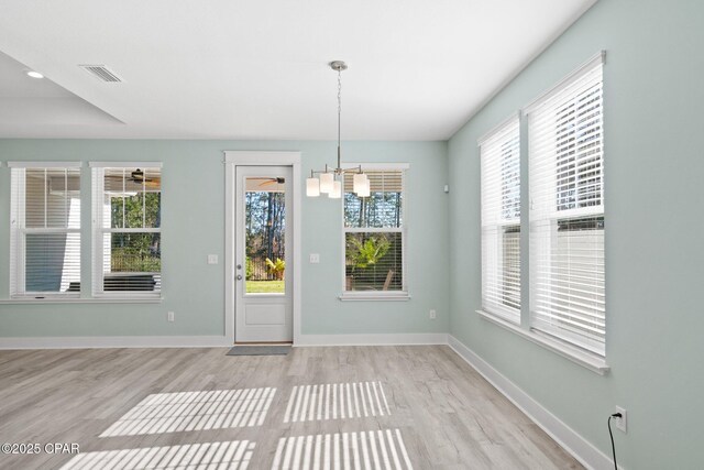 unfurnished dining area with a notable chandelier and light hardwood / wood-style floors