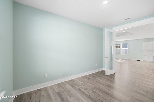 empty room with light hardwood / wood-style floors and french doors