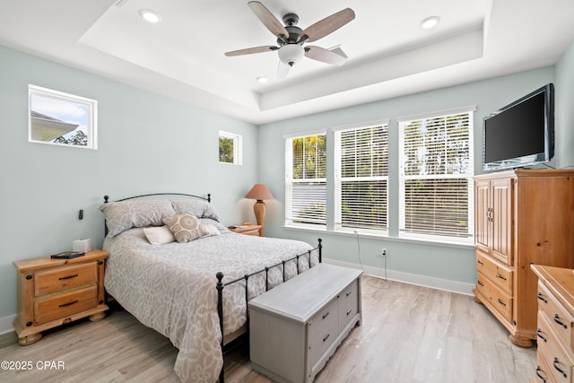 bedroom featuring ceiling fan, light hardwood / wood-style floors, and a raised ceiling