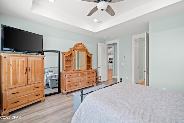 bedroom featuring a tray ceiling, light hardwood / wood-style flooring, and ceiling fan