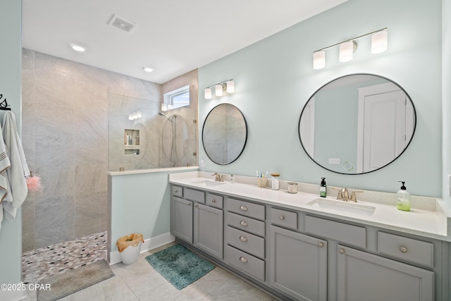 bathroom with tile patterned flooring, vanity, and tiled shower