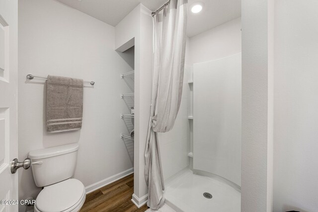 bathroom with a shower with shower curtain, toilet, and hardwood / wood-style floors