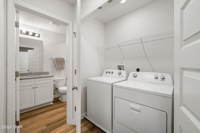 clothes washing area with washer and dryer, sink, and wood-type flooring