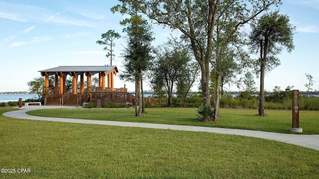 surrounding community with a water view and a lawn