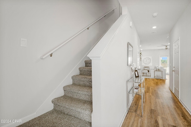 staircase featuring ceiling fan and wood-type flooring