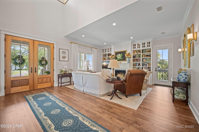 living room with french doors, plenty of natural light, crown molding, and hardwood / wood-style floors