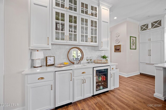 bar with white cabinetry, wine cooler, crown molding, and decorative backsplash