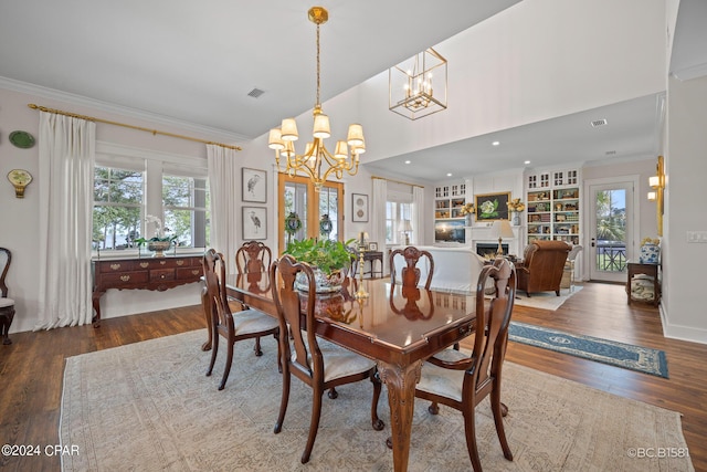 dining space featuring crown molding, a healthy amount of sunlight, hardwood / wood-style floors, and a chandelier