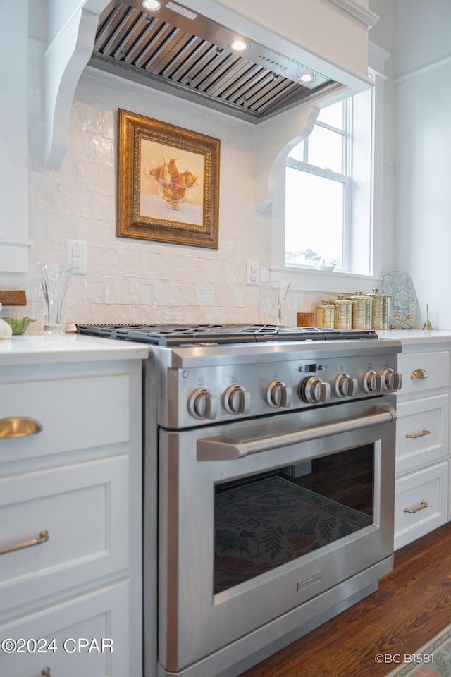 kitchen featuring premium range hood, white cabinetry, backsplash, dark hardwood / wood-style floors, and high end stove