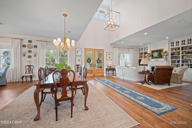 dining room featuring built in shelves, light hardwood / wood-style flooring, french doors, and a chandelier