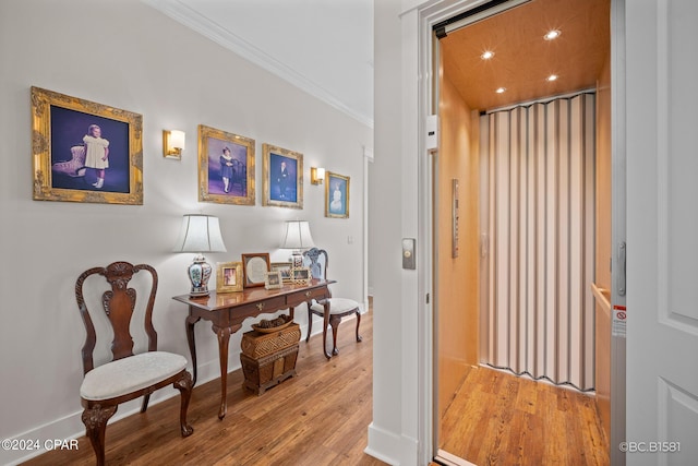 hall with crown molding, elevator, and light wood-type flooring