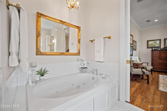 bathroom with an inviting chandelier, ornamental molding, wood-type flooring, and tiled tub