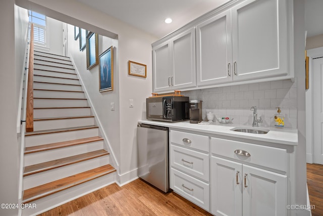 kitchen featuring refrigerator, tasteful backsplash, sink, white cabinets, and light hardwood / wood-style floors