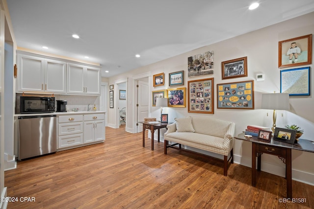 kitchen featuring white cabinetry, backsplash, stainless steel dishwasher, and light hardwood / wood-style floors