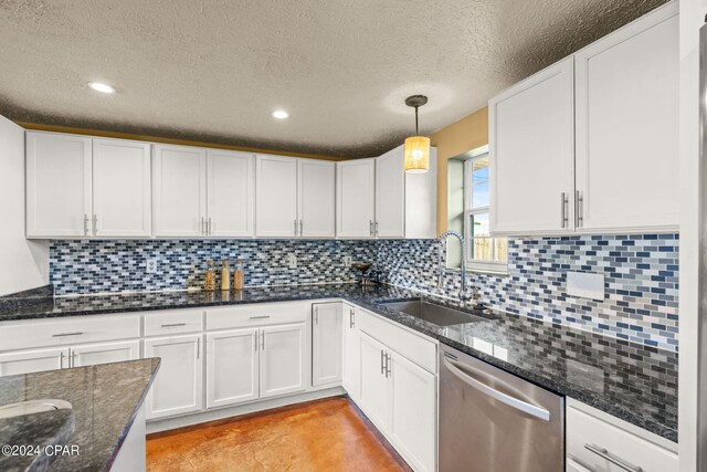 kitchen featuring dark stone countertops, sink, white cabinets, stainless steel dishwasher, and hanging light fixtures