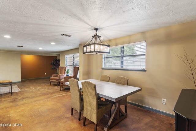 dining area with a textured ceiling, an inviting chandelier, and concrete floors