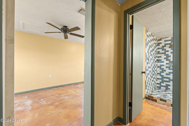 hall featuring concrete flooring and a textured ceiling