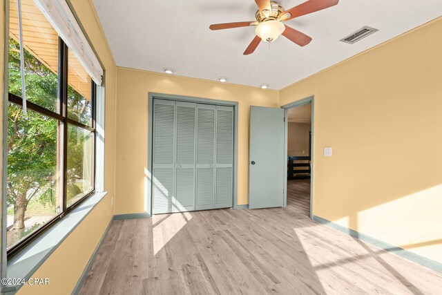 unfurnished bedroom featuring light hardwood / wood-style flooring, ceiling fan, and a closet