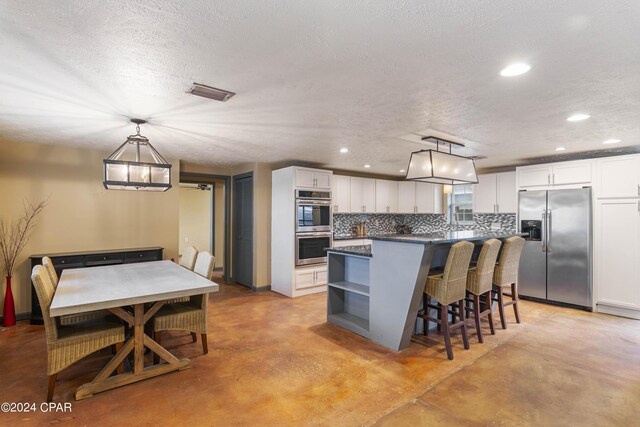 kitchen with white cabinetry, stainless steel appliances, a center island, backsplash, and pendant lighting