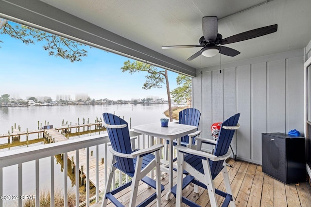 wooden terrace with ceiling fan, a water view, and a dock