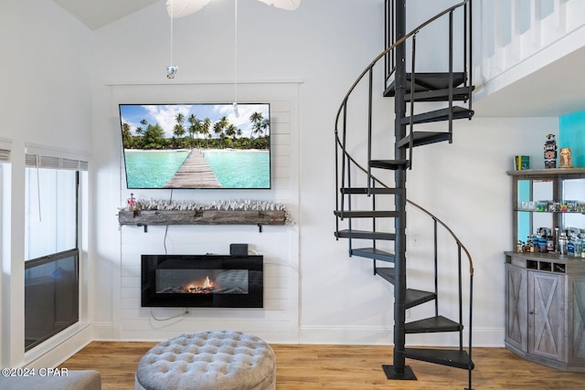 staircase with wood-type flooring, ceiling fan, and a high ceiling