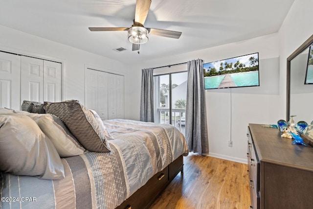 bedroom with ceiling fan, light hardwood / wood-style floors, and multiple closets