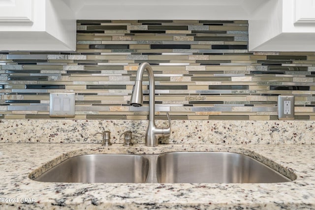 interior details featuring decorative backsplash, sink, and light stone countertops