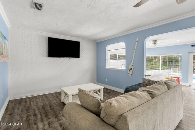 living room featuring a textured ceiling, ornamental molding, wood-type flooring, and ceiling fan