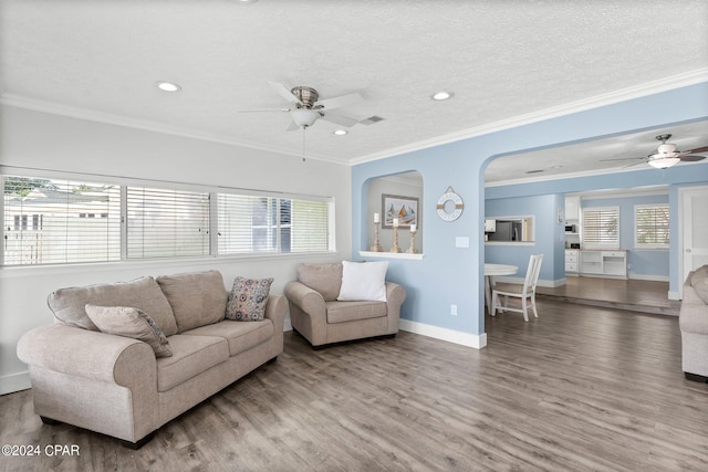 living room with a textured ceiling, wood finished floors, a ceiling fan, baseboards, and ornamental molding