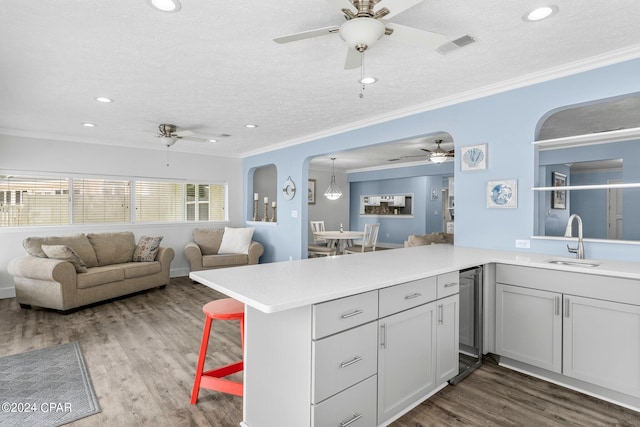 kitchen featuring arched walkways, light countertops, a sink, and wood finished floors