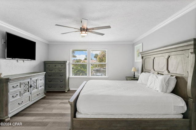 bedroom featuring ceiling fan, a textured ceiling, baseboards, ornamental molding, and light wood finished floors