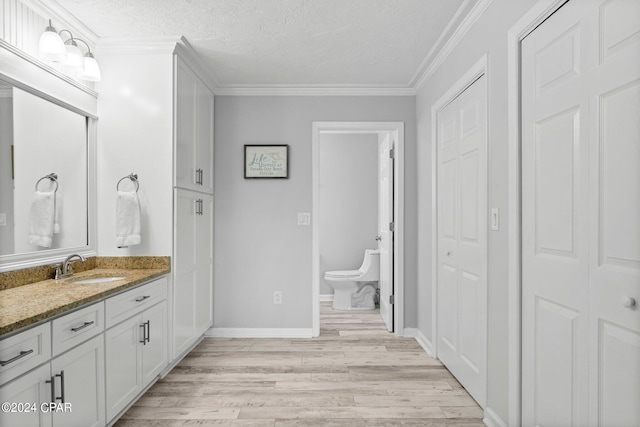 bathroom featuring a textured ceiling, toilet, vanity, hardwood / wood-style flooring, and ornamental molding