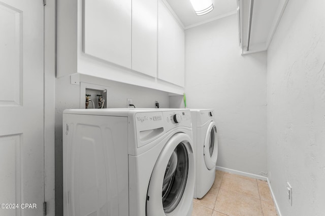 laundry room featuring light tile patterned floors, baseboards, cabinet space, washing machine and clothes dryer, and crown molding