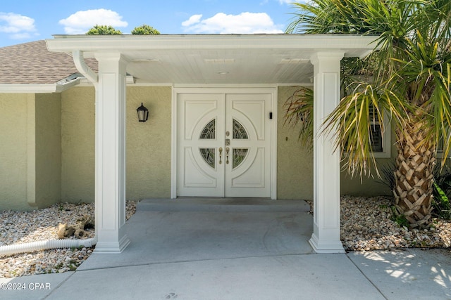 property entrance with a shingled roof and stucco siding