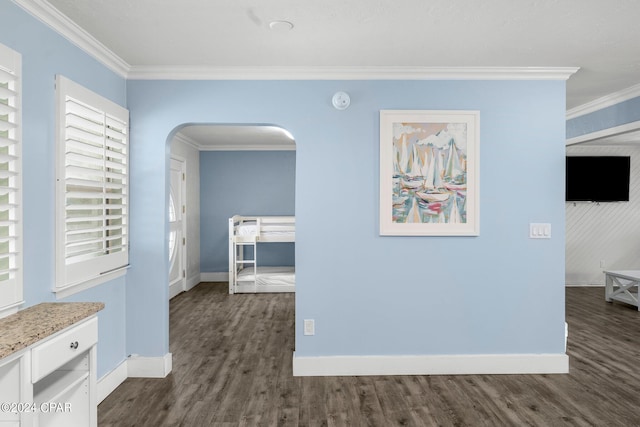 hall featuring crown molding, baseboards, arched walkways, and dark wood-type flooring