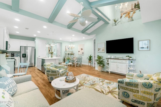 living room with ceiling fan with notable chandelier, sink, light hardwood / wood-style flooring, and vaulted ceiling with beams