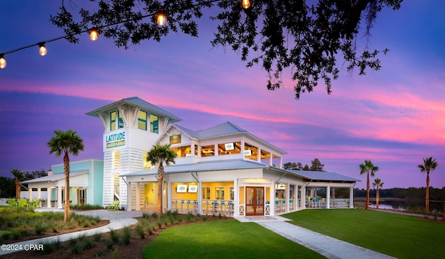 back house at dusk with a balcony and a yard