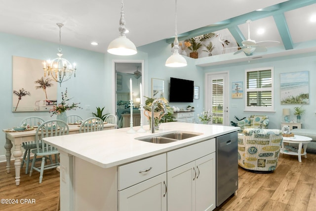 kitchen featuring a center island with sink, stainless steel dishwasher, sink, white cabinetry, and hanging light fixtures