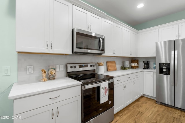 kitchen with stainless steel appliances, light hardwood / wood-style floors, white cabinets, and decorative backsplash