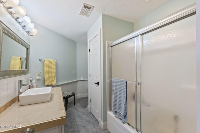 bathroom featuring tasteful backsplash, tile patterned flooring, a textured ceiling, vanity, and a shower with shower door