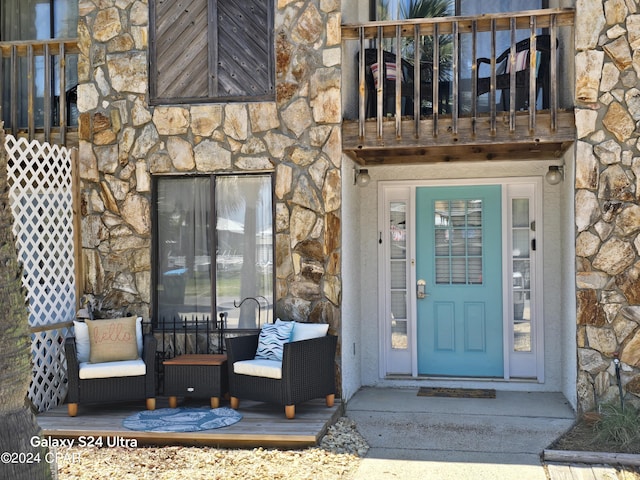 entrance to property featuring stone siding and a balcony