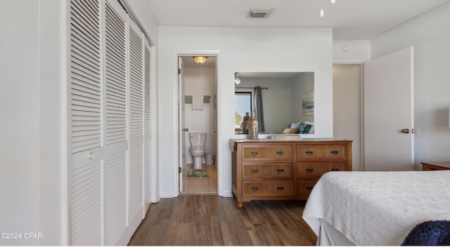 bedroom featuring dark wood-type flooring, a closet, visible vents, and ensuite bath