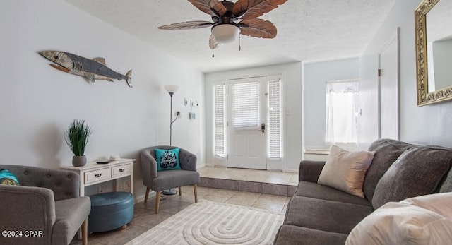 tiled living room with ceiling fan, baseboards, and a textured ceiling