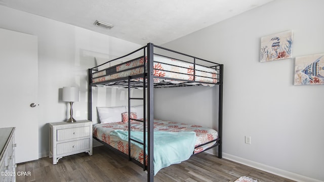 bedroom featuring visible vents, baseboards, and wood finished floors