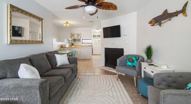 living area featuring a fireplace, a ceiling fan, and light tile patterned flooring