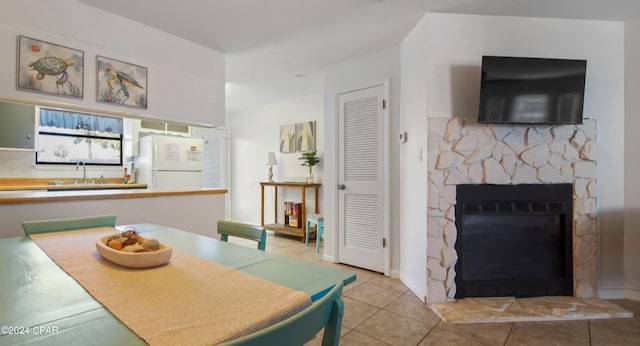 tiled dining space with a sink and a stone fireplace