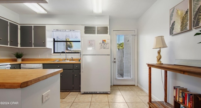 kitchen with light tile patterned floors, white appliances, a sink, and a wealth of natural light