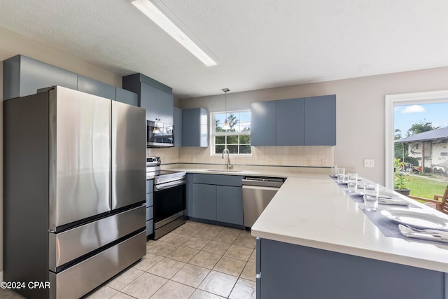 kitchen with hanging light fixtures, backsplash, kitchen peninsula, and stainless steel appliances